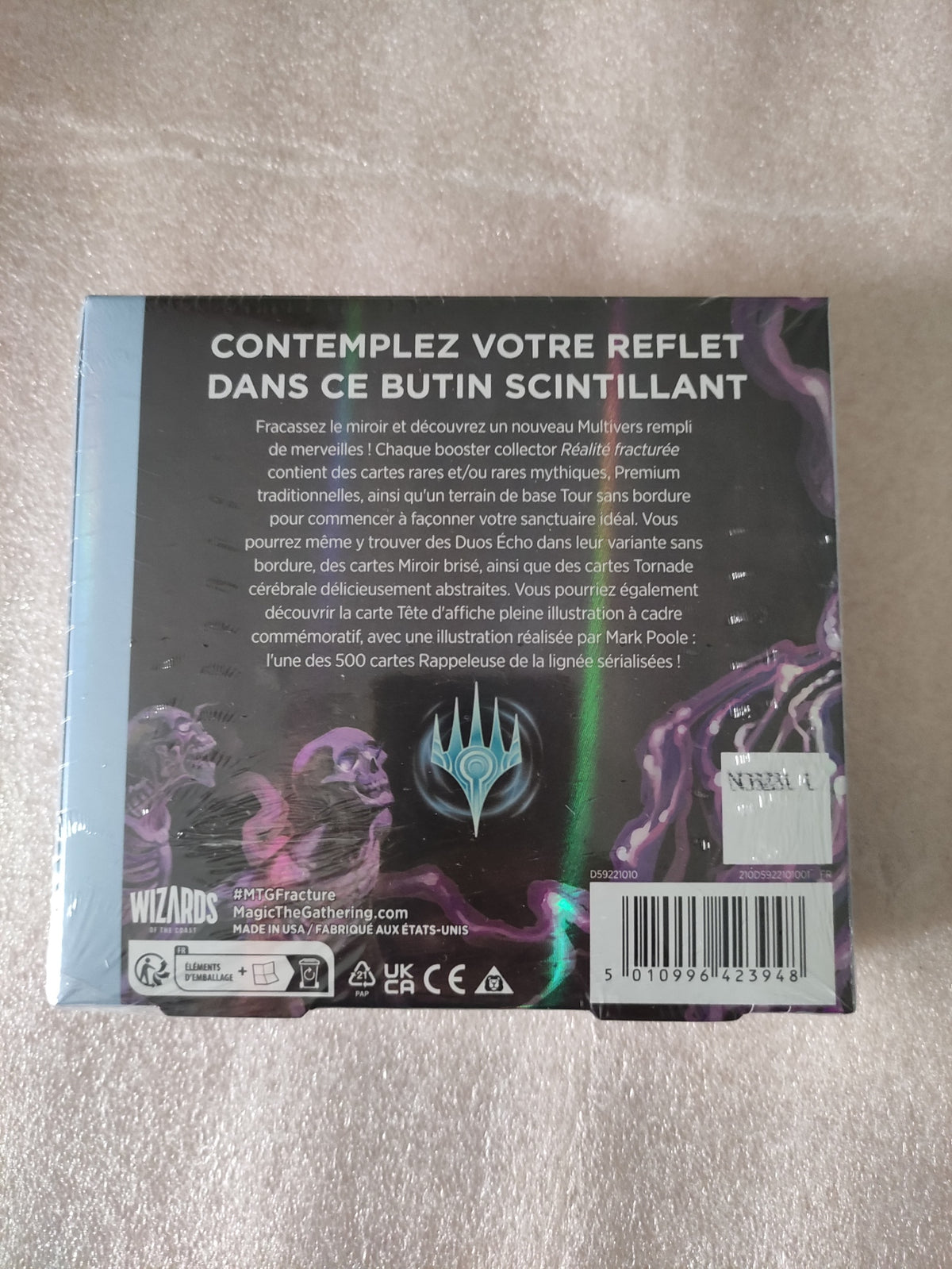 Display de 12 boosters Magic: The Gathering – Réalité fracturée par Wizards of the Coast, avec cartes en main.